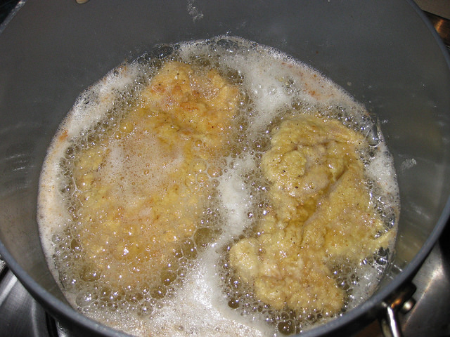 Flour coated chicken is frying in oil.