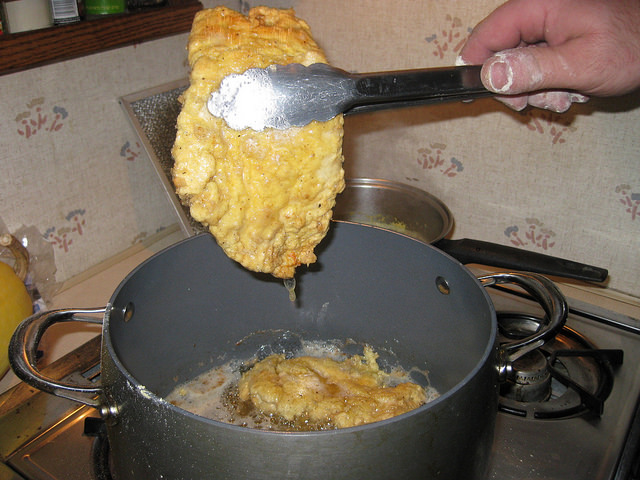 Removing the chicken when it is crispy and golden brown.