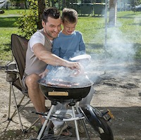 A father teaching his young son how to barbeque. 