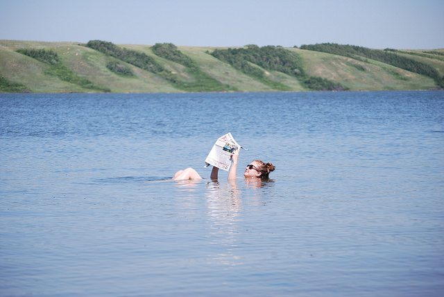 A woman reading a newspaper while floating on the mineral unfused waterof Little Manitou Lake.