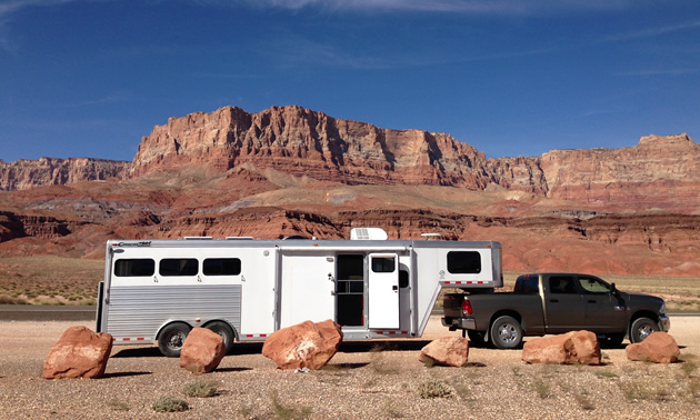 A gooseneck horse trailer with living quarters pulled by a black dodge truck. 