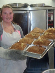 A baker taking fresh loaves out of the oven.