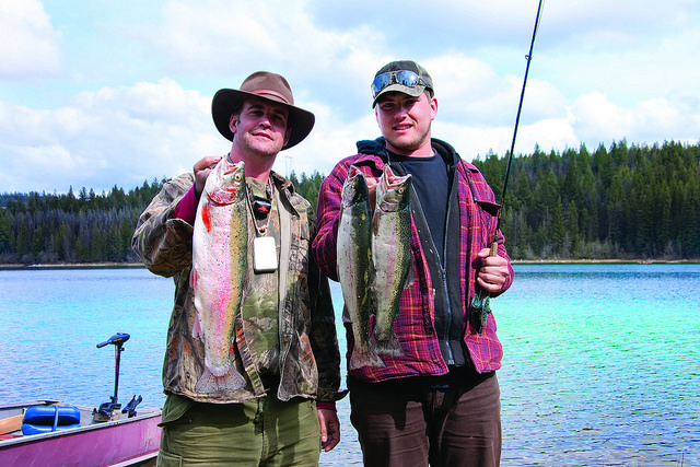 Two men holding up the fish they caught.