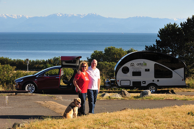 Oetter and Sommerfeld embark on a cross-country journey with their dog, Kye, as seen in this photo standing with their electric car and trailer behind them. 