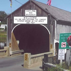 Photo of a large covered bridge with a road going through it. 