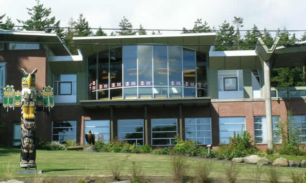 Large glassed face building with totem pole        