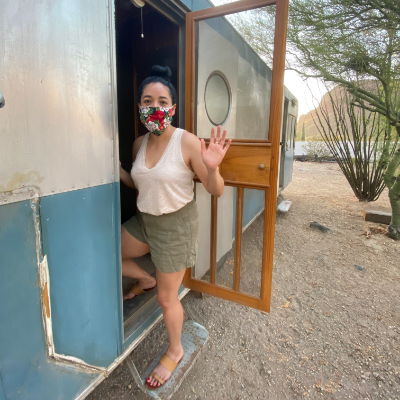 Stephanie Loya waves while entering her blue and white 1953 28-foot Platt Trail-a-Home travel trailer.