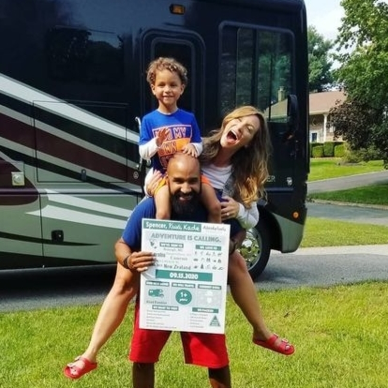 Family of three - mom, dad and child, in front of a Class A RV