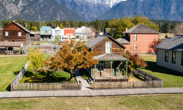 1890s-style homes and buildings reside in a rustic-looking environment with trees changing colours in fall