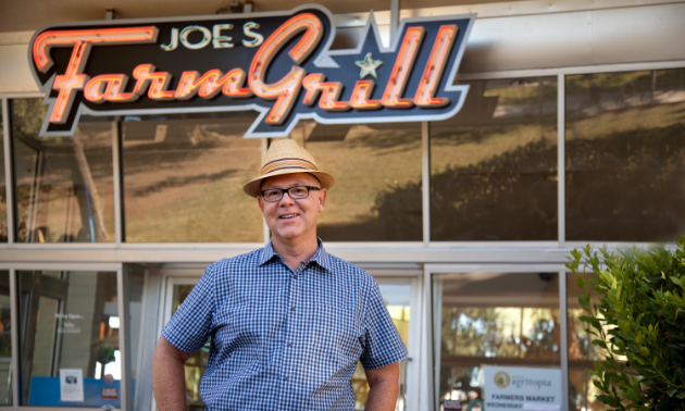 Joe Johnston, the owner of Joe's Farm Grill, a ranch-style family homestead restaurant, smiles in front of his business.