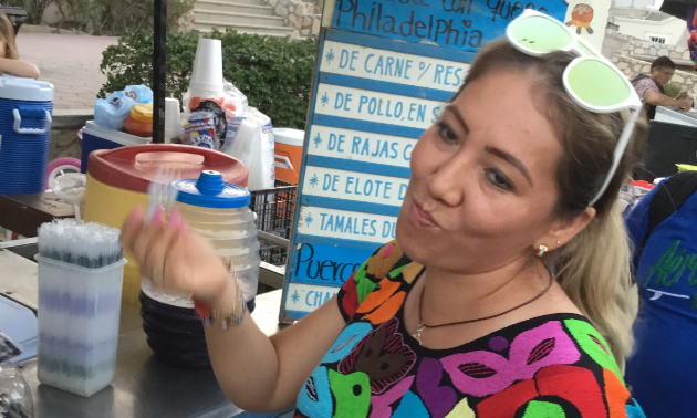 A woman enjoys a taco at a taco stand