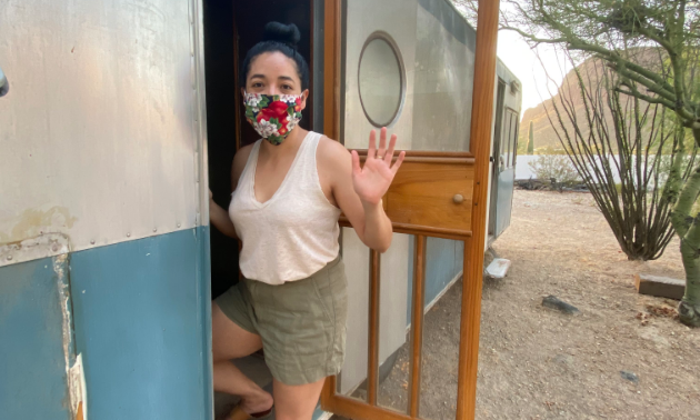 Stephanie Loya waves while entering her blue and white 1953 28-foot Platt Trail-a-Home travel trailer.