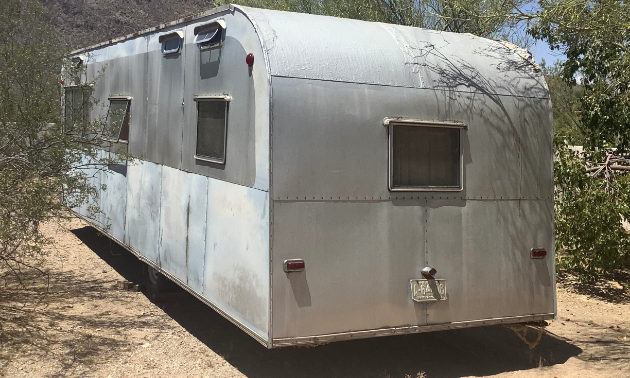 The grey exterior of a 1953 28-foot Platt Trail-a-Home travel trailer.