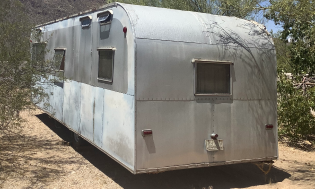 The grey exterior of a 1953 28-foot Platt Trail-a-Home travel trailer. 