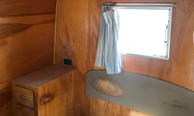Wood panelling lines the inside of a 1953 28-foot Platt Trail-a-Home travel trailer. 