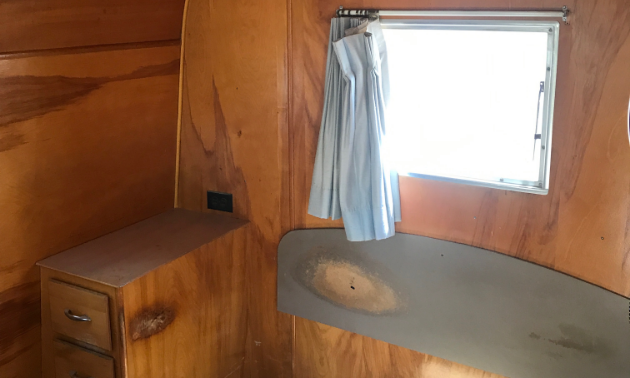 Wood panelling lines the inside of a 1953 28-foot Platt Trail-a-Home travel trailer.