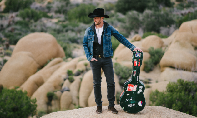 Paul Brandt poses with his guitar in the desert