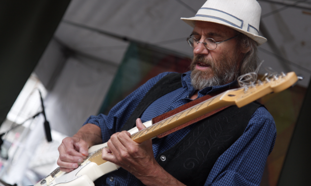 An elderly man shreds up a sweet lick on guitar.