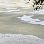 A picture showing the beach with the tide out, there a large sandy area with pockets of water that goes on until it reaches the ocean. 