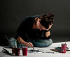 The artist Siobhan Humston sitting cross legged on the floor painting one of her pictures. 