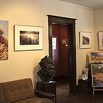 This picture shows the inside of the gallery, with a couple of flower paintings, as well as 4 black and white prairie scene photographs. 