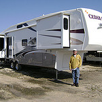 A man standing in front of his large RV home.