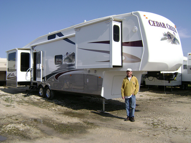 A man standing in front of his large RV home.