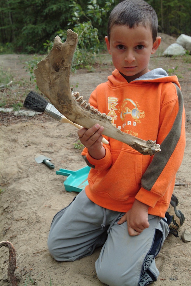 Little boy holding a jaw bone that he helped dig.