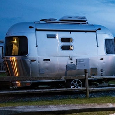 Airstream Caravel model parked at spot near ocean. 