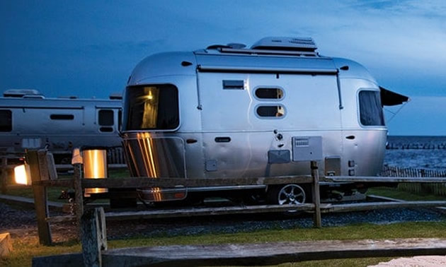 Airstream Caravel model parked at spot near ocean. 