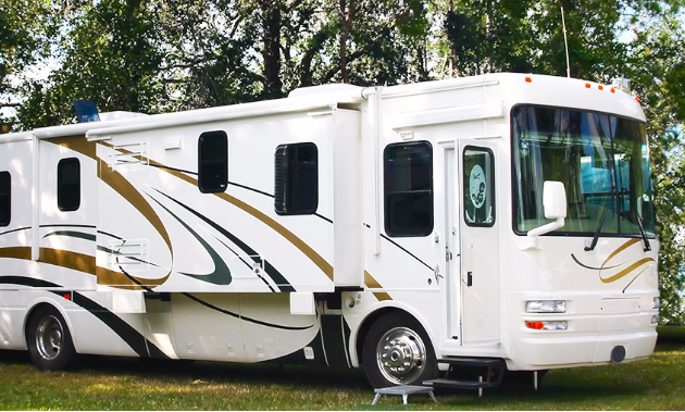 A large motorhome parked in a treed spot