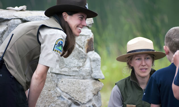 Picture of two park rangers interacting with a child. 