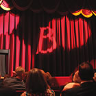 a red velvet curtain hangs at the front of a theatre stage