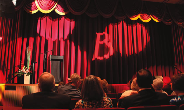a red velvet curtain hangs at the front of a theatre stage