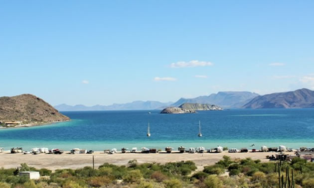 A vast expanse of white sand beach, with a turquoise-coloured ocean in the background and blue sky. 