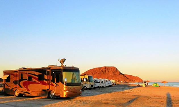 A golden-coloured sunrise, with a fifth wheel in the foreground. 