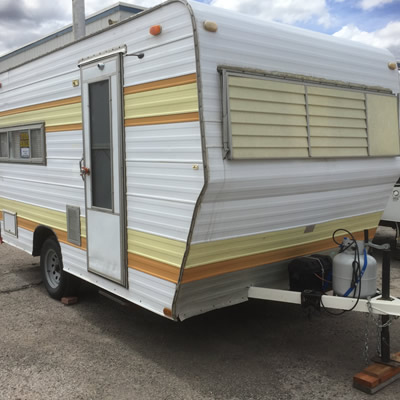 A yellow and brown striped trailer sitting on a sales lot. 