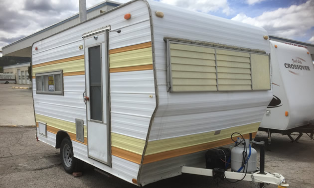 A yellow and brown striped trailer sitting on a sales lot. 