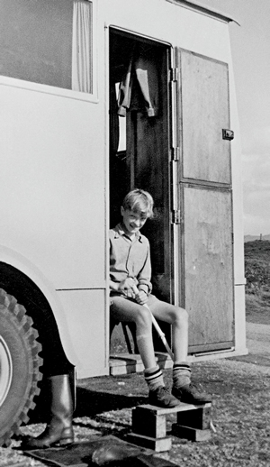 Stefan Sykut, as a young boy, sits in the door of his grandfather's wooden RV.