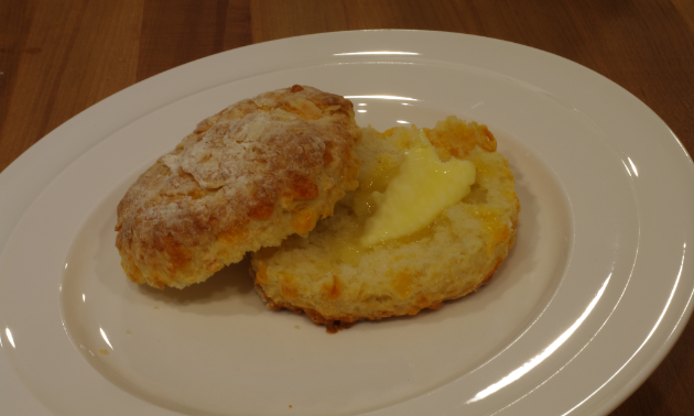 A buttered buttermilk biscuit sits on a plate.