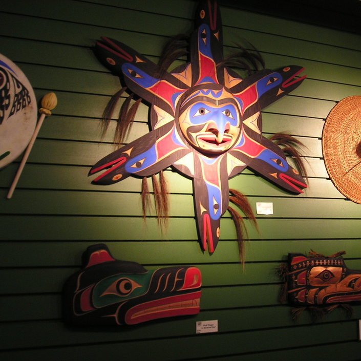 The Sun Mask, a piece by Wilson George, is surrounded by other works of art.
