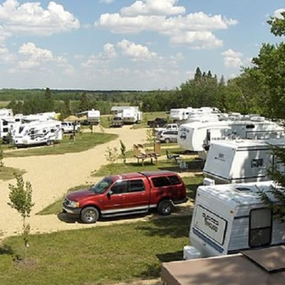 View of campers and RV parked in a campground. 