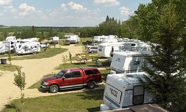 View of campers and RV parked in a campground. 