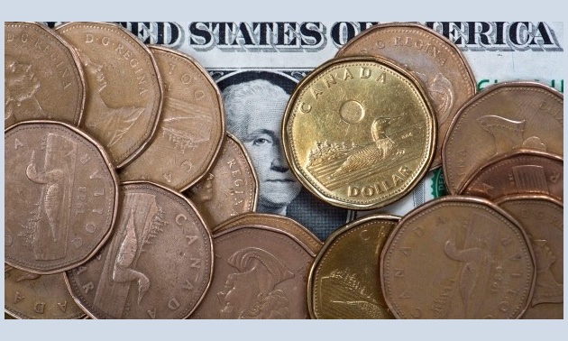 A number of loonies sitting on top of an American dollar bill.