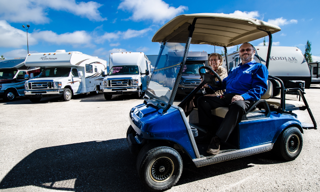 A salesperson shows a customer the various RVs by cruising around the lot in a golf cart