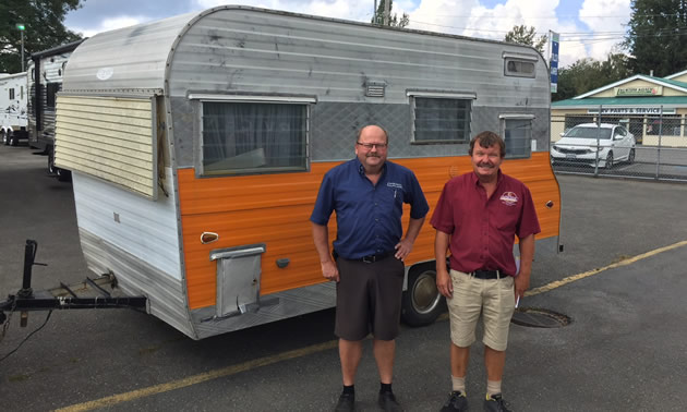 The two sons of Kustom Koach founder Carl Carstensen standing in front of trailer. 