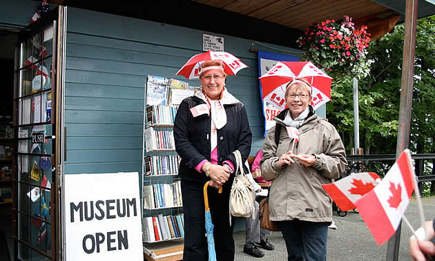 Two German tourists wearing umbrella hats with Canadian flag print