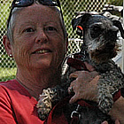 Woman holding small dog stands beside her RV unit.