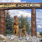 wooden carvings of bears under a welcome to Chetwynd sign