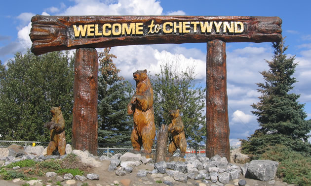 wooden carvings of bears under a welcome to Chetwynd sign